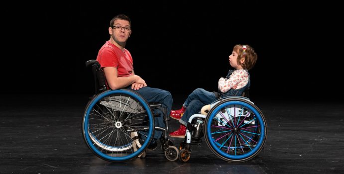 宣傳照：一位小女孩在輪椅上雙臂交叉放在胸前，面向着一位同樣在輪椅上的男子；而男子雙手放在大腿上，面向着鏡頭。